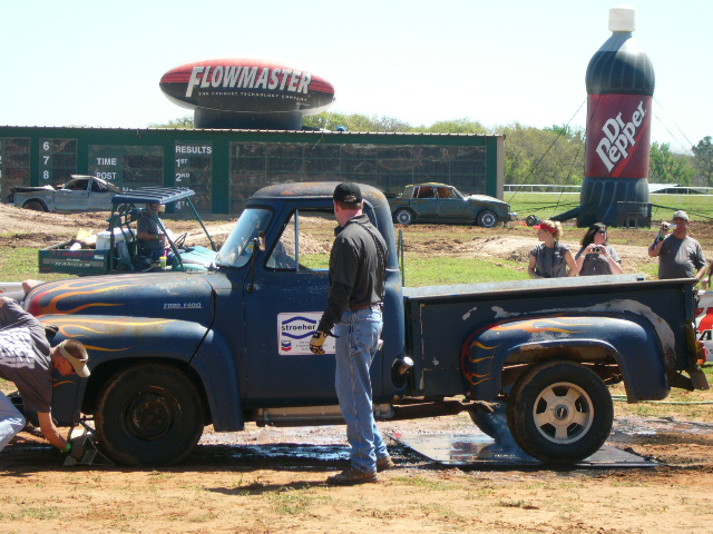 Side view of a blue 1953 Ford F-100 pickup truck with flames painted on the hood and bed
