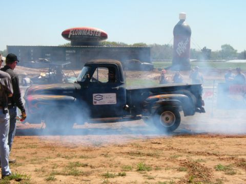 1978 Ford Bronco - A black pickup truck from the 1950s is seen performing a burnout, with smoke billowing around it.