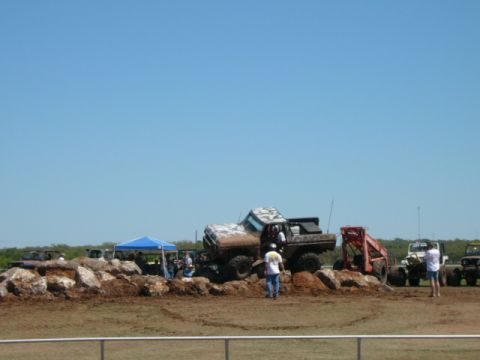 1978 Ford Bronco - Several off-road vehicles navigate a rocky obstacle course under a clear blue sky.