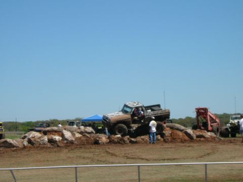 1978 Ford Bronco - Off-road trucks tackle a challenging rock obstacle course under a clear blue sky.