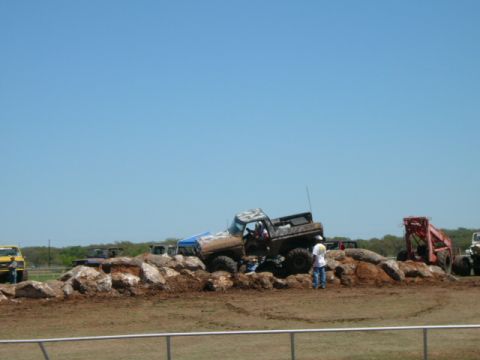 1978 Ford Bronco - A lifted pickup truck navigates a rocky obstacle course under a clear blue sky.