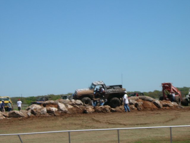 Mud-covered pickup truck with a lifted suspension driving over rocks