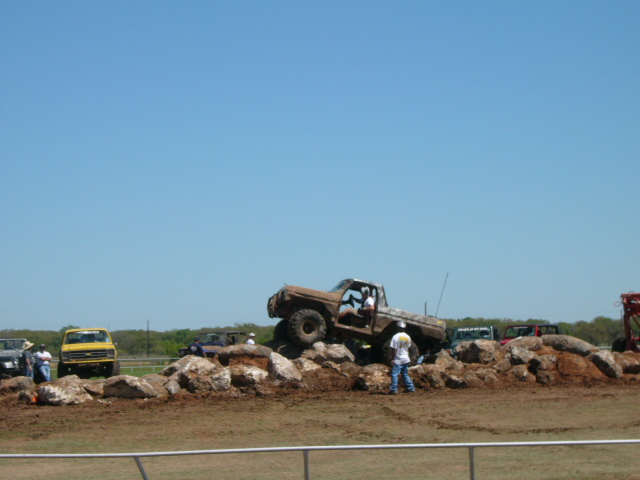 1978 Ford Bronco climbing over rocks with people watching