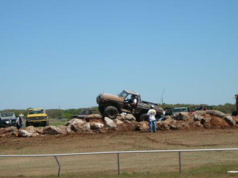 1978 Ford Bronco - A lifted, mud-covered truck navigates a rocky obstacle course on a sunny day.