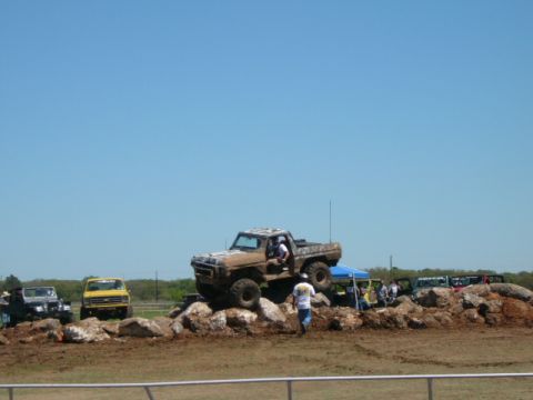 1978 Ford Bronco - A modified truck navigates a rocky obstacle course under a clear blue sky.