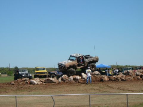 1978 Ford Bronco - Several off-road vehicles navigate a rocky obstacle course under a clear blue sky.