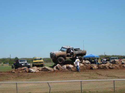 1978 Ford Bronco - Off-road vehicles navigate a challenging obstacle course under a clear blue sky.