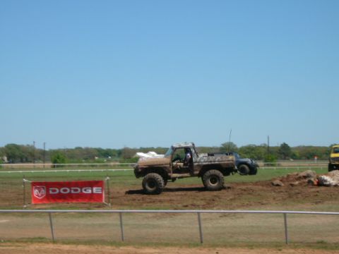 1978 Ford Bronco - A muddy pickup truck navigates a dirt track, with a Dodge banner visible in the background.
