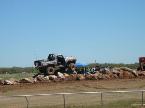 1978 Ford Bronco - A modified pickup truck navigates a rocky obstacle course under a clear blue sky.