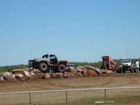 1978 Ford Bronco - A mud-splattered 1978 Ford Bronco navigates a rocky terrain, with other off-road vehicles visible in the background.