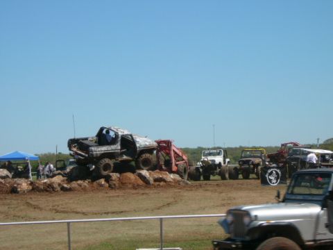 1978 Ford Bronco - Multiple modified off-road vehicles are gathered at an outdoor event under a clear blue sky.
