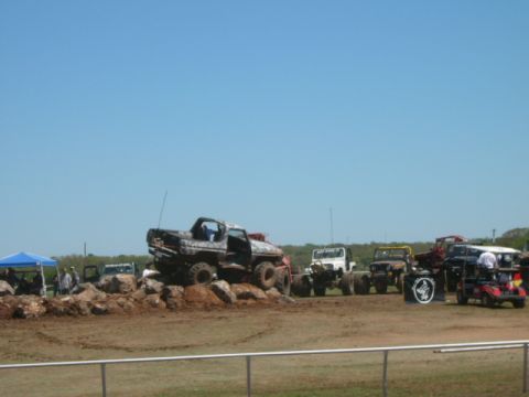 1978 Ford Bronco - A collection of vehicles are parked on a dirt course under a clear blue sky.