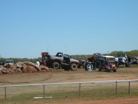 1978 Ford Bronco - Multiple off-road vehicles, including a 1978 Ford Bronco, are gathered on a dirt track during a competition.