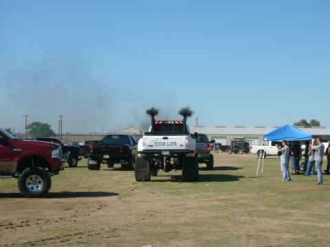 1978 Ford Bronco - Modified pickup trucks with tall stacks are seen in a field, with one truck emitting black smoke.