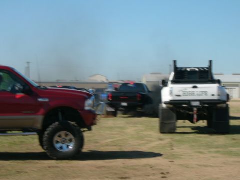 1978 Ford Bronco - Multiple trucks are visible in an outdoor lot under a clear blue sky.