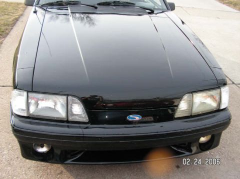 1988 Ford Mustang - Front view of a black 1988 Ford Mustang, its distinctive headlights and blue oval emblem.