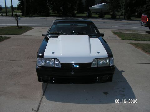 1988 Ford Mustang - A black and white Ford Mustang with a prominent aftermarket hood is parked on a driveway.