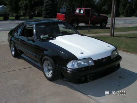 1988 Ford Mustang - This black and white 1988 Ford Mustang features a prominent white cowl induction hood and aftermarket wheels.