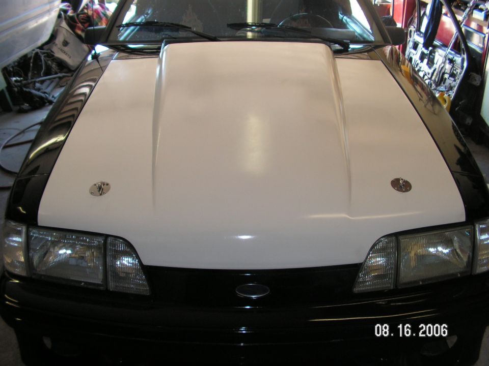 Car front with a white hood scoop and black fenders. Has two hood pins