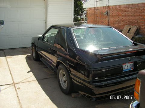 1988 Ford Mustang - Black 1988 Ford Mustang coupe parked in front of a garage.