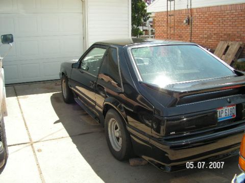1988 Ford Mustang - Black 1988 Ford Mustang coupe with a spoiler, parked in a driveway.
