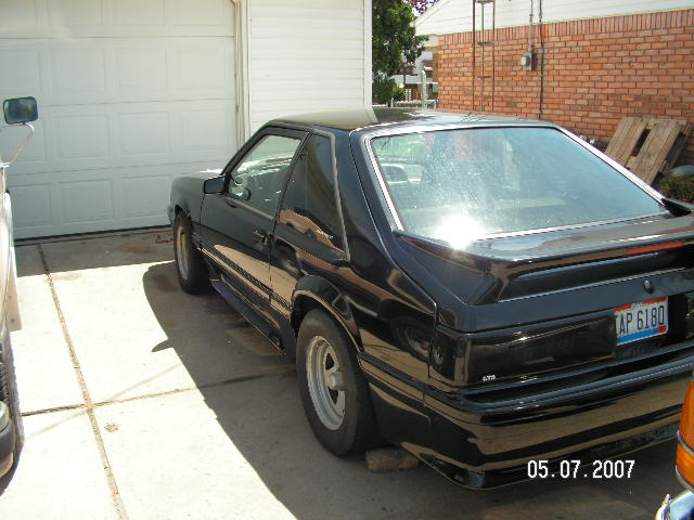 1988 Ford Mustang coupe, rear 3/4 view, parked in driveway next to garage