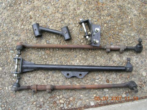 1996 Ford Bronco - Several automotive steering linkage parts are displayed on a textured concrete surface, with a date stamp visible in the lower right corner.