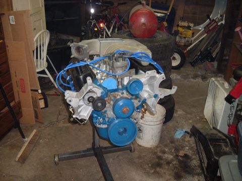 1990 Ford Ranger - A Ford V8 engine, painted blue and silver, is mounted on an engine stand in a cluttered garage setting.