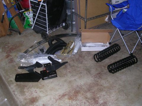 1994 Ford Bronco - Various vehicle suspension components are organized on the floor, possibly for installation or storage.