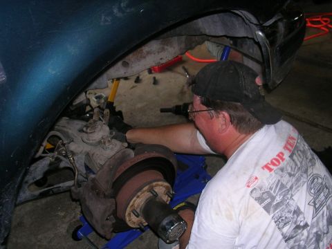 1994 Ford Bronco - A mechanic is shown working on the suspension of a vehicle, with various tools and equipment around.