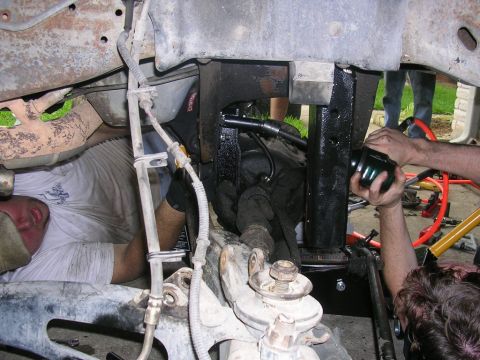 1994 Ford Bronco - Several people are working on the suspension and drivetrain components of a vehicle.