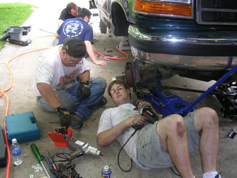 1994 Ford Bronco - Men work on the front suspension of a green Ford truck.