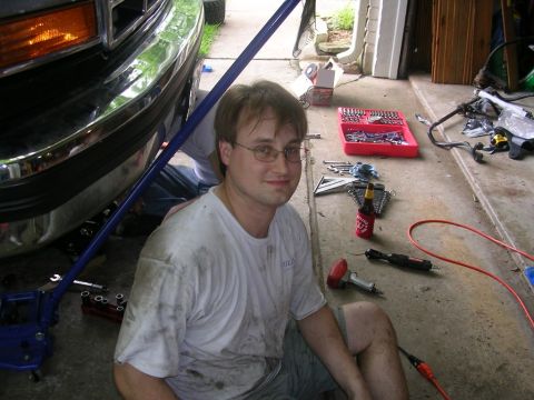 1994 Ford Bronco - Man works on the front end of a 1994 Ford Bronco in a garage with tools scattered around.