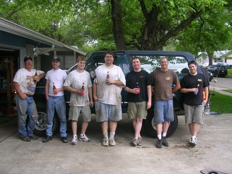 Group of men with beer bottles in front of a 1994 Ford Bronco