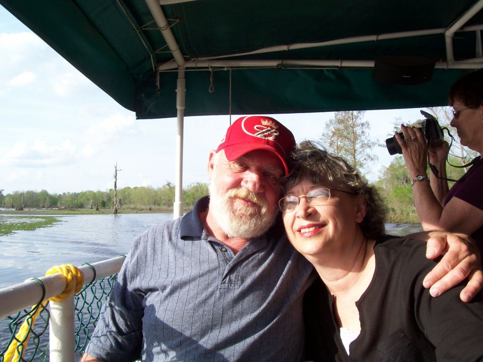 Couple smiling on a boat with trees and water in the background