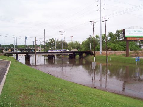 1992 Ford Bronco - A bridge crosses over a flooded area, with power lines and a billboard in the background under an overcast sky.
