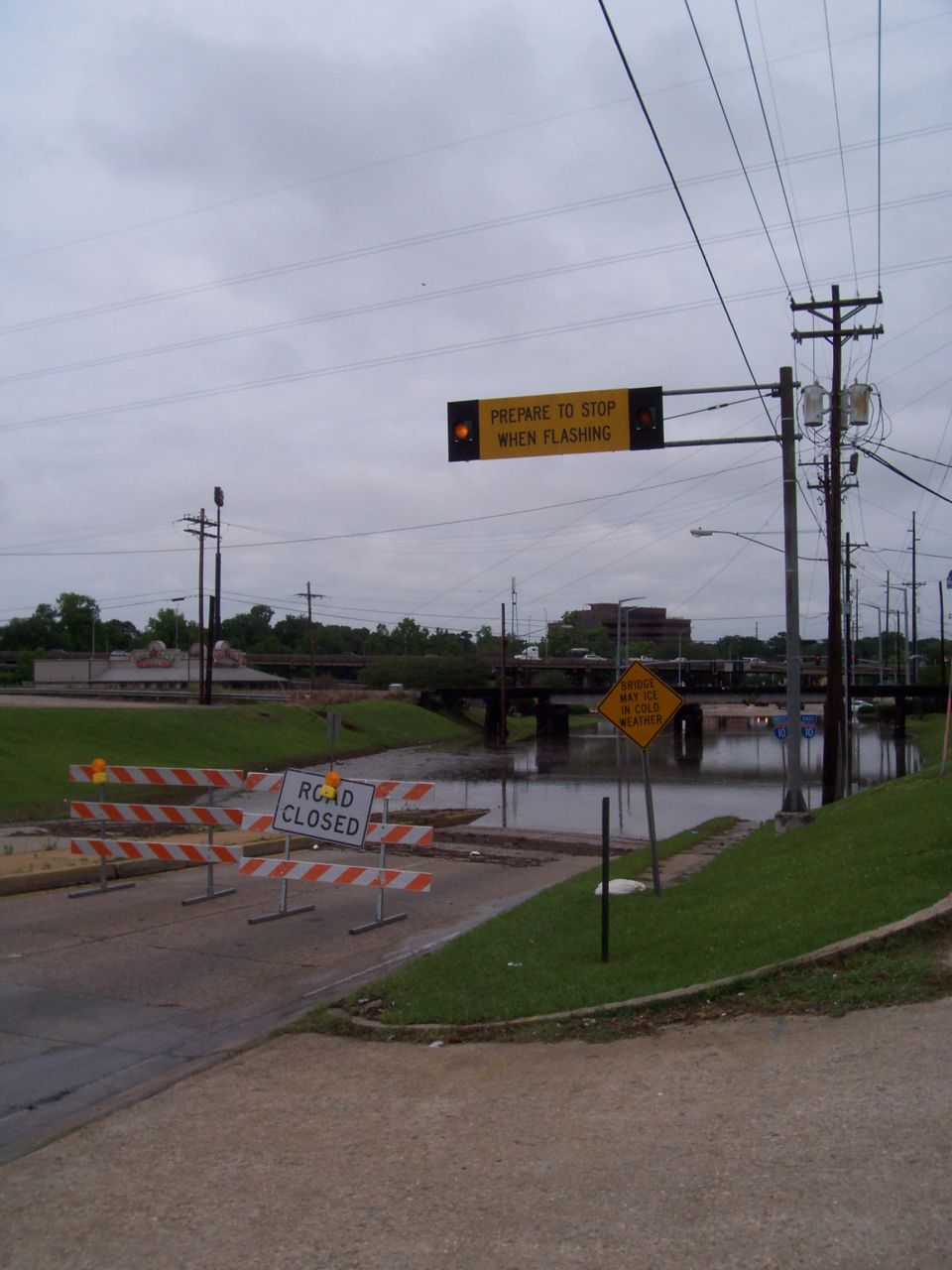 Road closed sign and barriers with flooded roadway and flashing traffic signal