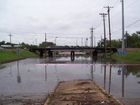 1992 Ford Bronco - A flooded road under a bridge, with signs indicating I-10 East, on a cloudy day.