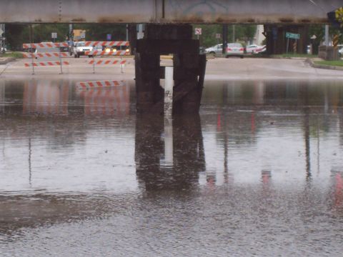 1992 Ford Bronco - Water covers the road under a bridge, with traffic barriers and vehicles in the background.