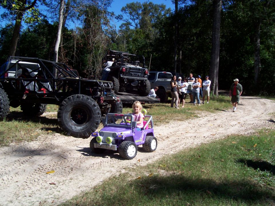 Purple toy jeep with a child driving on a dirt path