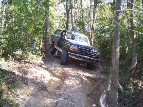 1992 Ford Bronco - This 1992 Ford Bronco is navigating a steep, muddy trail through a forest.