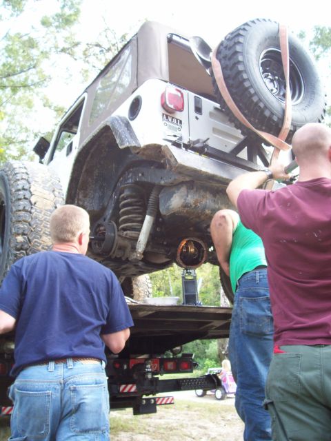 1992 Ford Bronco - Men working on the rear axle of a Jeep Wrangler on a flatbed trailer.