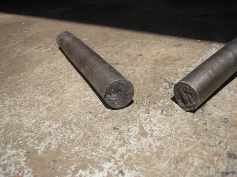1990 Ford Bronco - Two metal rods lie on a concrete surface, one showing a ribbed texture and both with fractured ends.