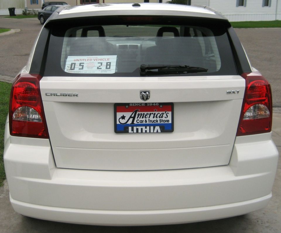 Rear of a white Dodge Caliber SXT with dealer plate
