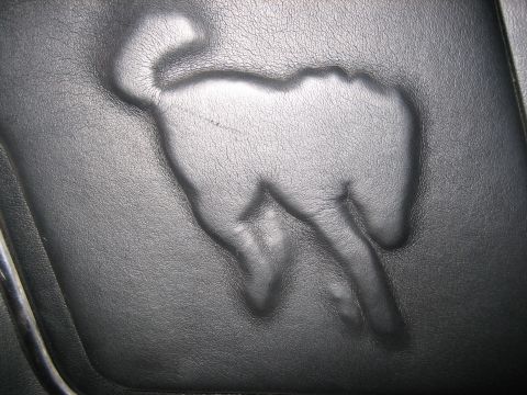 1990 Ford Bronco - A close-up of a horse logo embossed into a black leather surface, possibly a car seat.