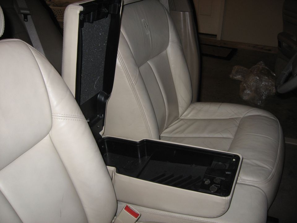 Tan leather seats with center console armrest open showing empty storage bin