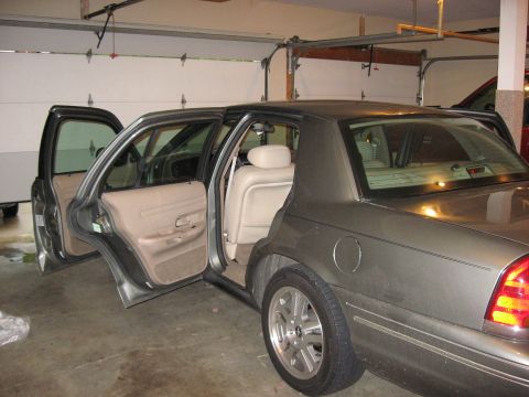 2001 Ford Crown Victoria - Rear passenger side view of a gray 2001 Ford Crown Victoria with its doors open inside a garage.