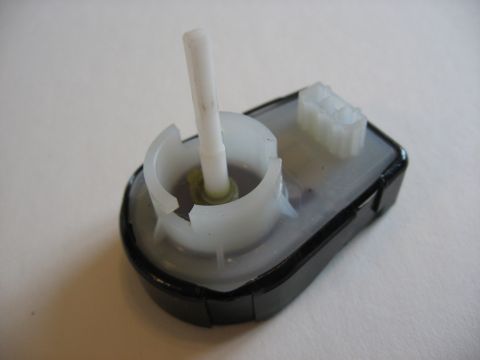 2001 Ford Crown Victoria - Close-up of a small plastic gear motor assembly on a white surface.