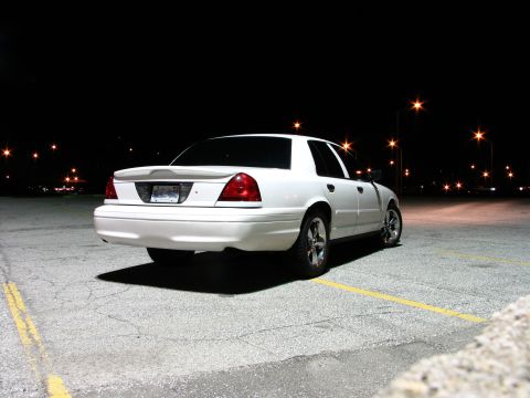 2003 Ford Crown Victoria - A white 2003 Ford Crown Victoria is parked in a lot at night, viewed from the rear quarter angle.