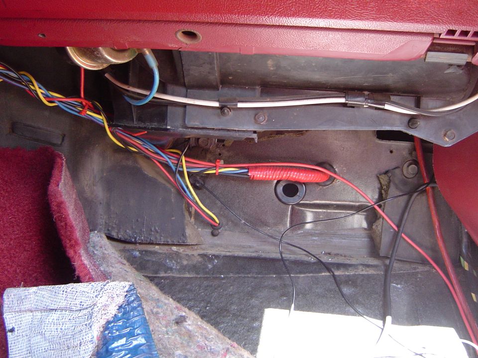 Under-dash wiring harness with red power lead routed to a firewall grommet